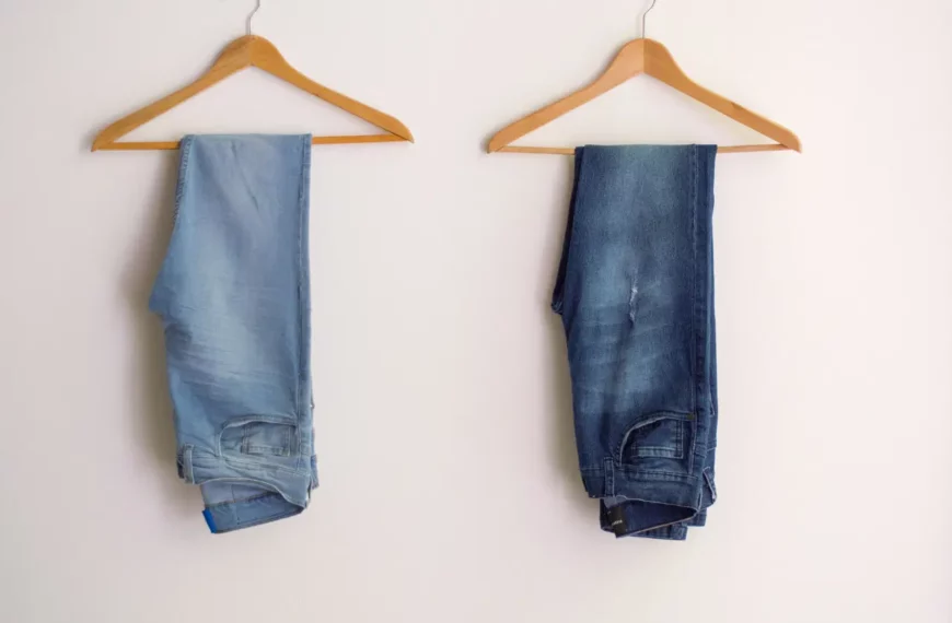 two pairs of jeans, one light one dark, hanging next to each on brown hangers