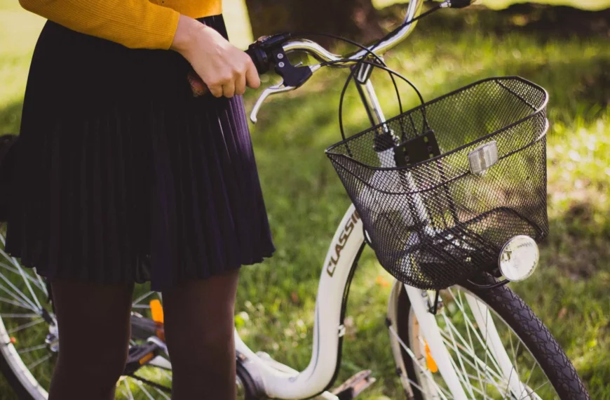 close up of person wearing black pleated skirt, black tights, yellow top, holding onto a bike by the handles