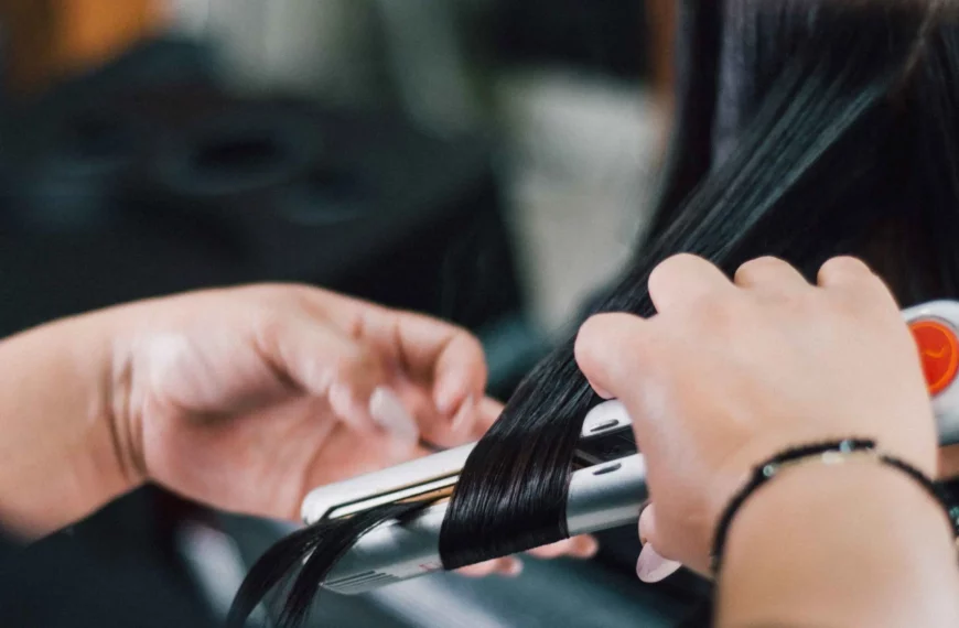 close up of hands using a hair straightener on long dark hair