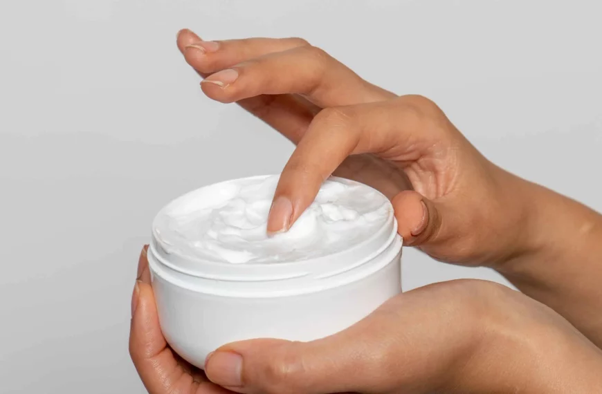 close up of person's hands dipping finger into container of lotion