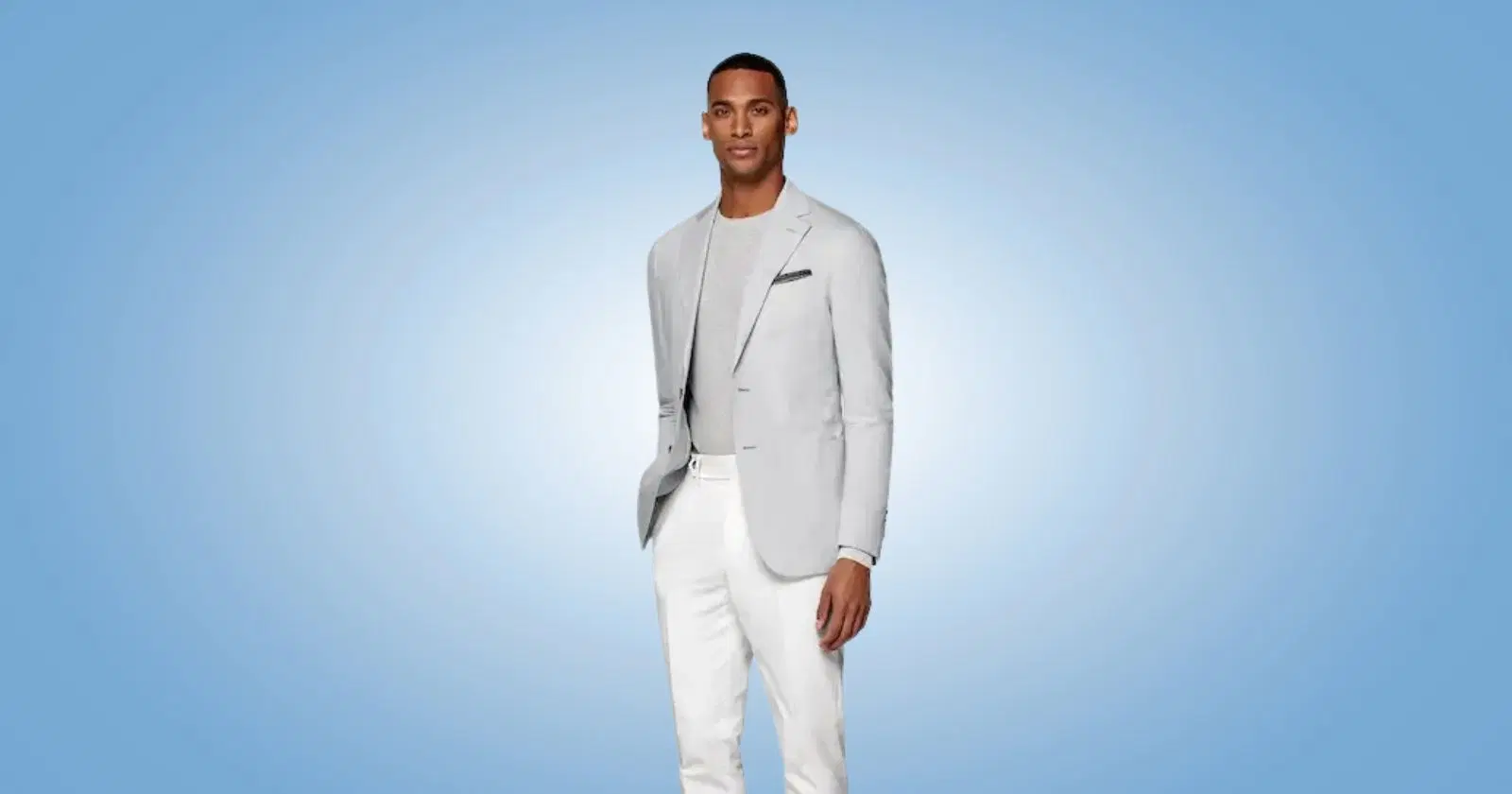 man looking into camera wearing gray suit jacket, shirt, and white pants from suitsupply