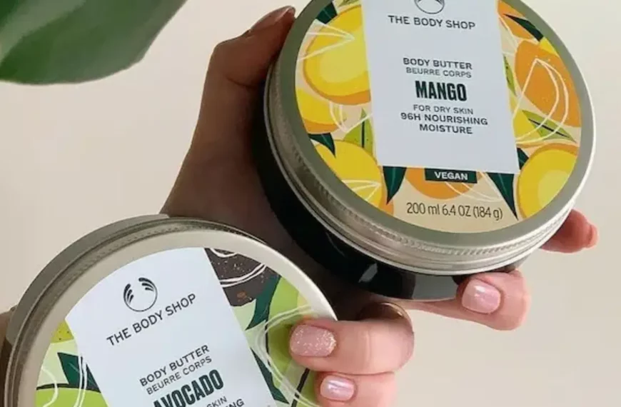 persons hand holding two jars of the body shop body butters