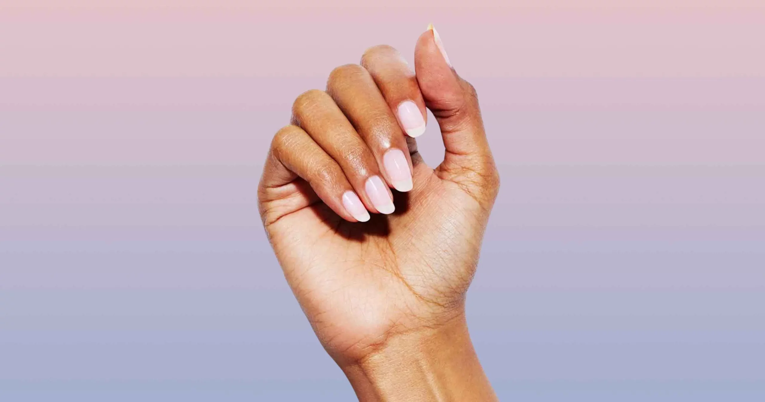 close up of woman's hand with fingernails painted a sheer pink color from Static Nails