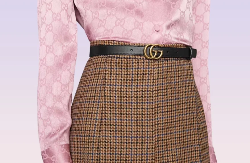 closeup of person wearing pink top, patterned skirt, and Gucci black leather double g belt